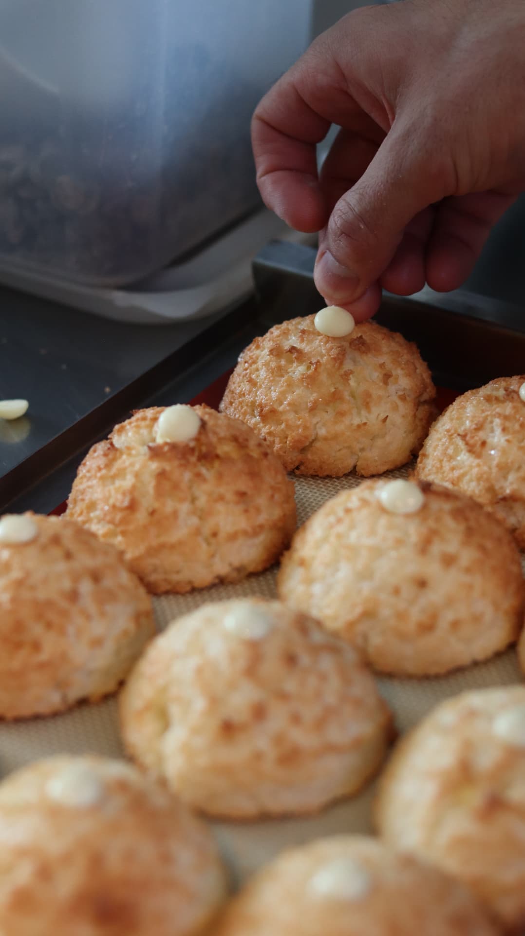 Kokosmacronen worden afgewerkt met witte chocolade